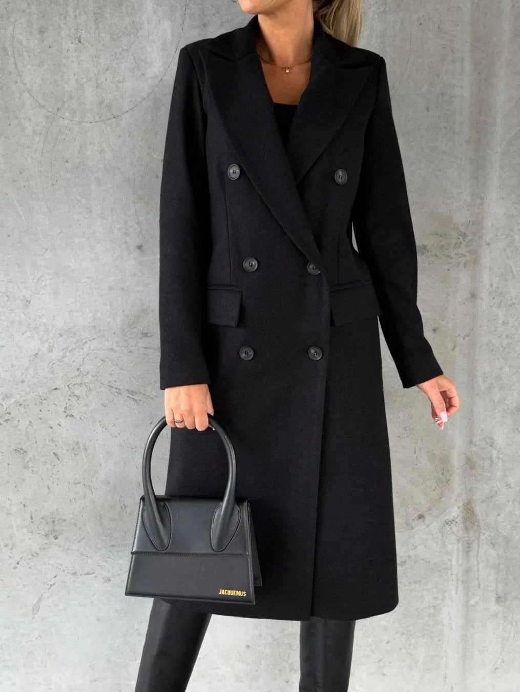 Cappotto nero elegante donna, doppio petto, abbinato a borsa nera di design, moda autunno inverno, stile sofisticato e moderno.