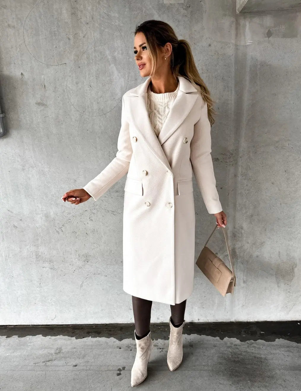 Donna con cappotto bianco elegante, borsa beige e stivali chiari su sfondo grigio. Moda invernale, stile chic, abbigliamento femminile.