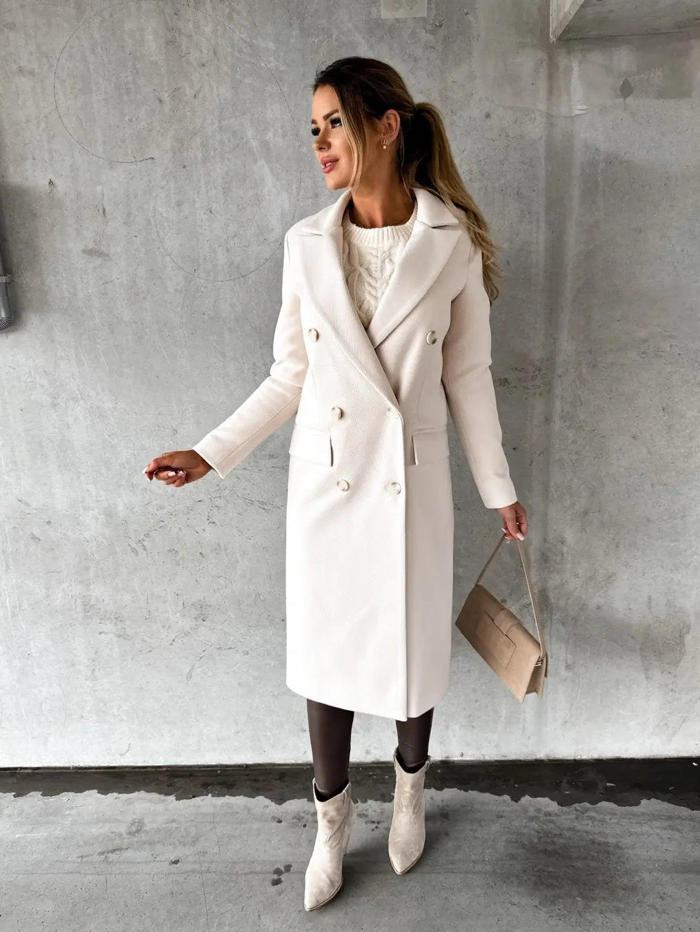 Donna con cappotto bianco elegante, borsa beige e stivali chiari su sfondo grigio. Moda invernale, stile chic, abbigliamento femminile.