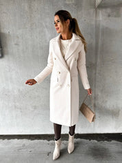 Donna con cappotto bianco elegante, borsa beige e stivali chiari su sfondo grigio. Moda invernale, stile chic, abbigliamento femminile.