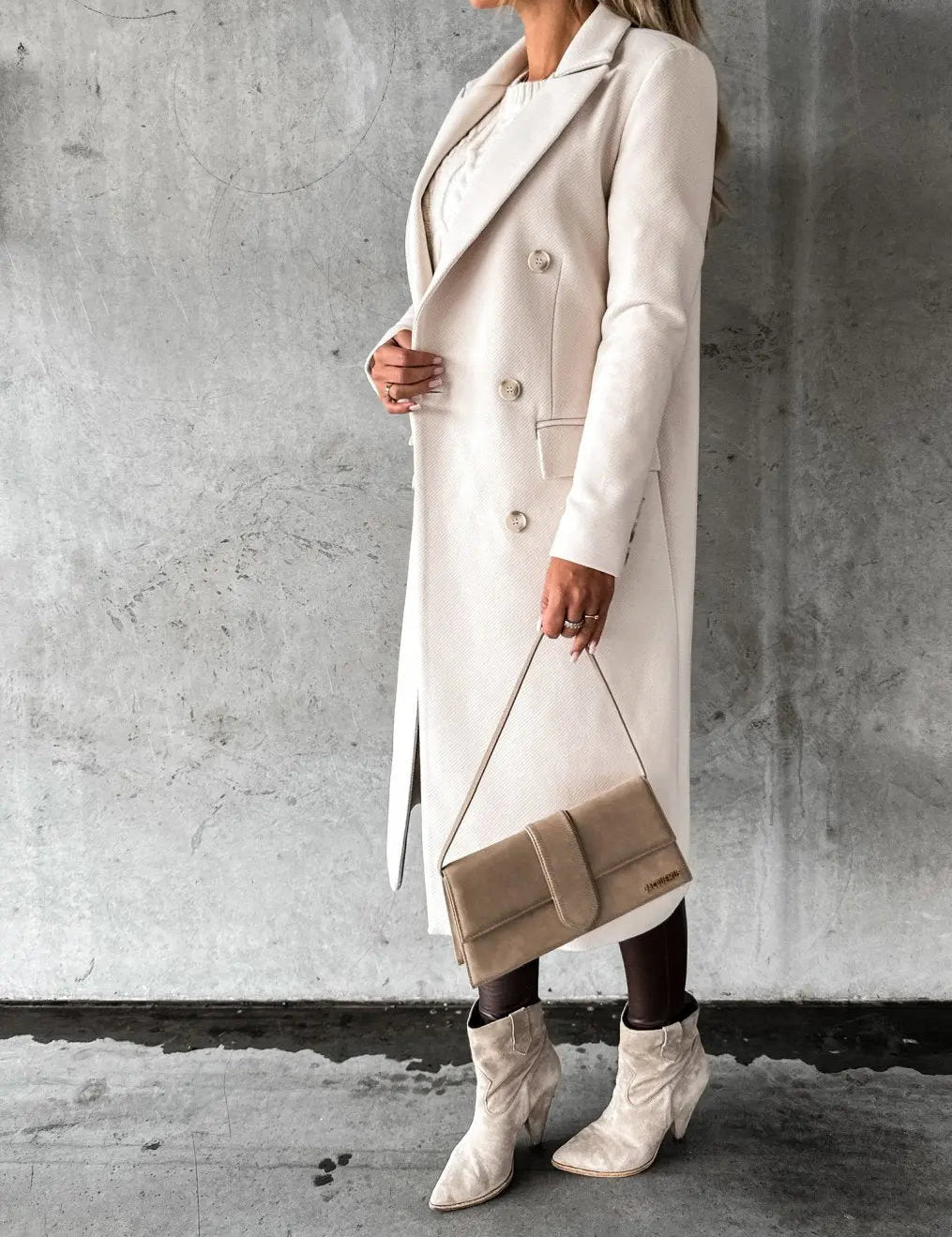Cappotto lungo beige elegante, donna in posa con borsa a tracolla e stivali coordinati, moda autunno inverno, abbigliamento femminile chic.