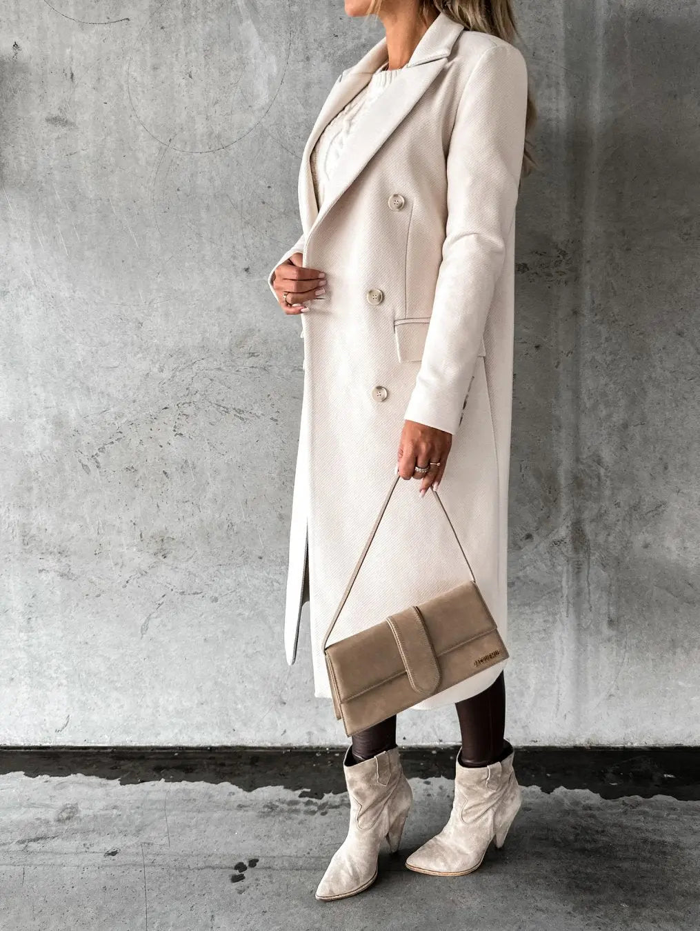Cappotto lungo beige elegante, donna in posa con borsa a tracolla e stivali coordinati, moda autunno inverno, abbigliamento femminile chic.