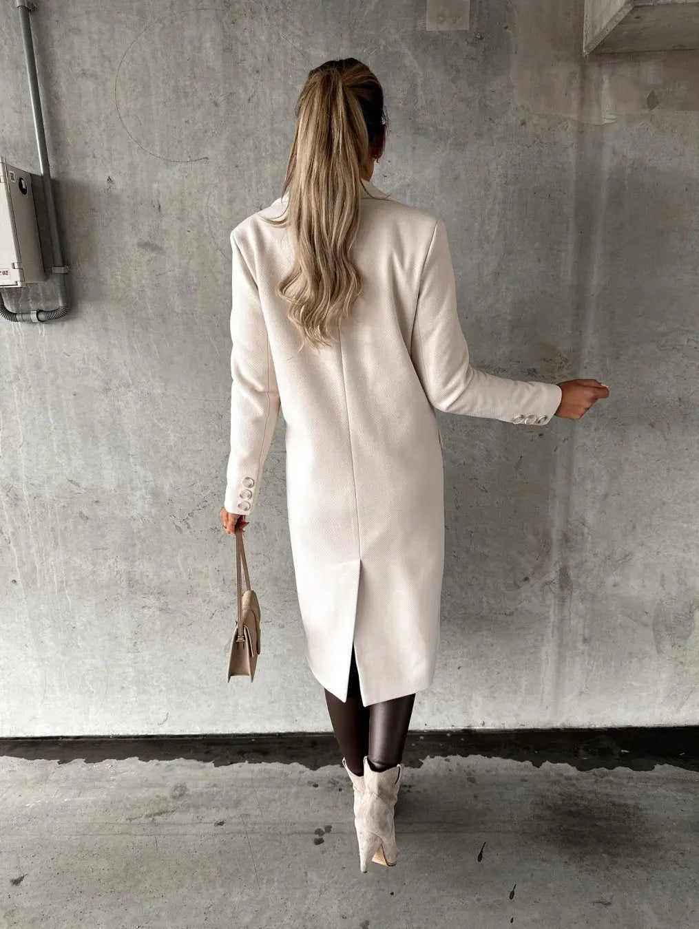 Donna di spalle con cappotto bianco elegante, stivali beige e borsa a mano. Moda autunnale, stile sofisticato, abbigliamento femminile di tendenza.