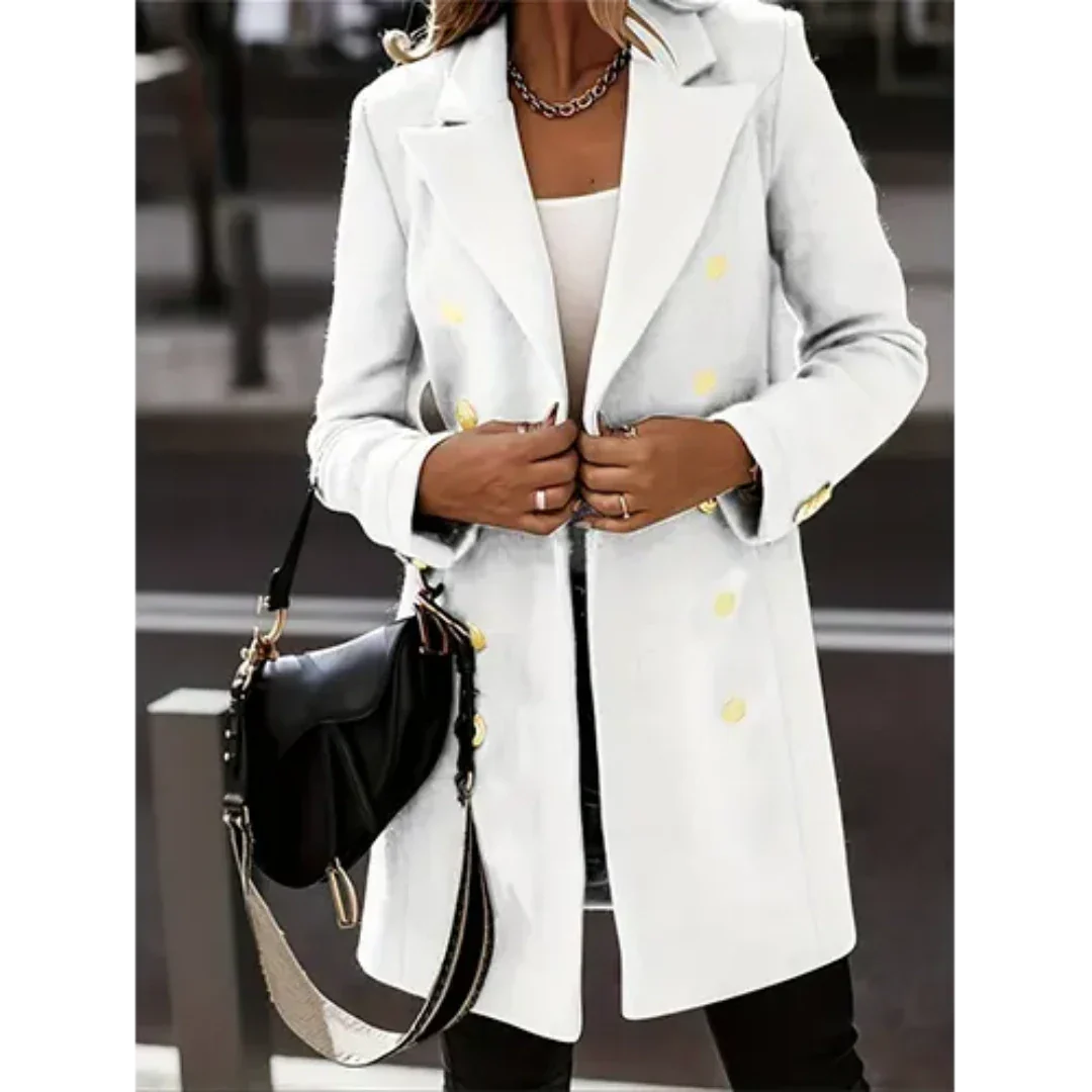 Cappotto bianco elegante da donna con bottoni dorati, indossato su top bianco. Accessoriato con borsa nera a tracolla. Moda autunnale chic.