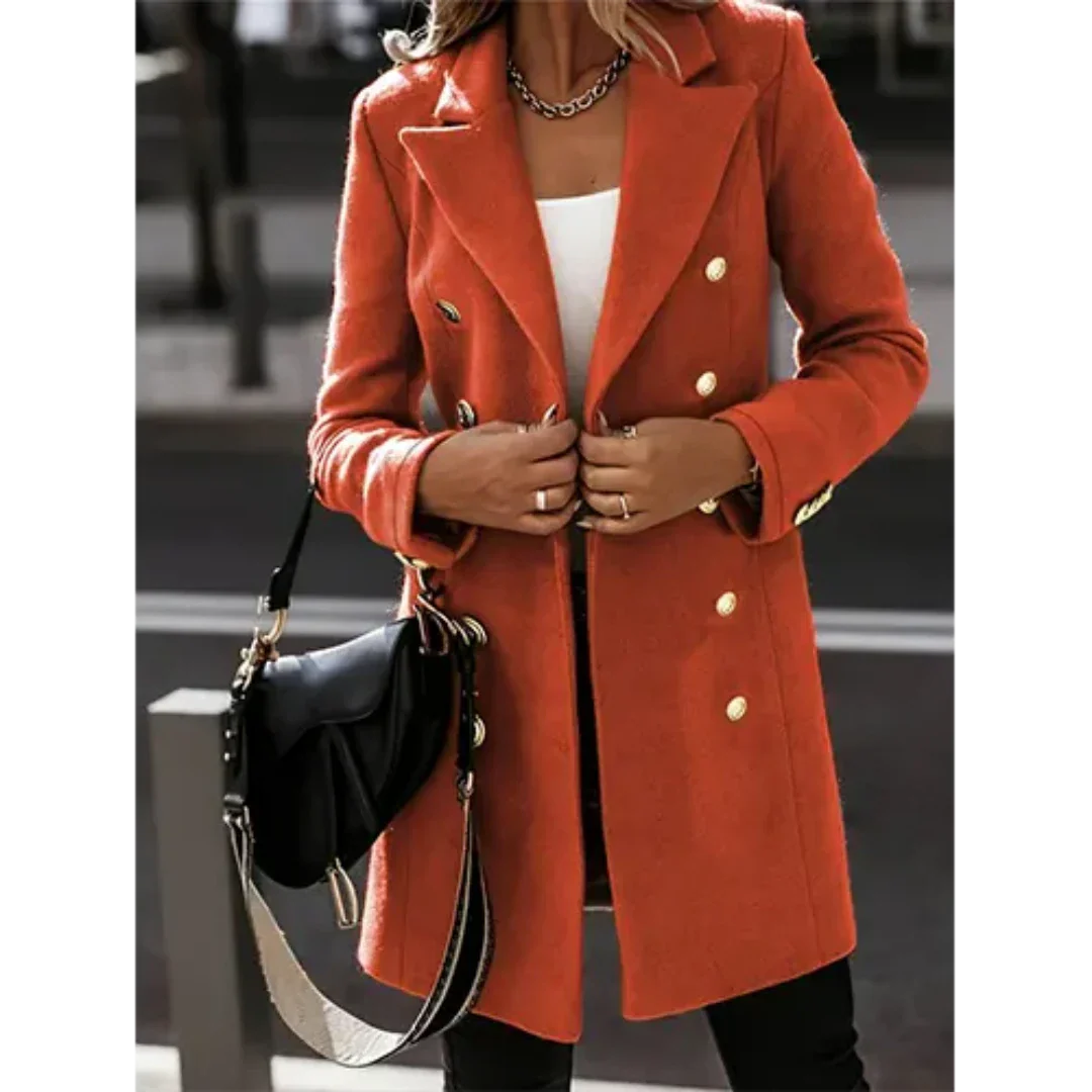 Cappotto arancione elegante da donna con bottoni dorati, indossato su top bianco. Accessoriato con borsa nera a tracolla. Moda autunnale chic.