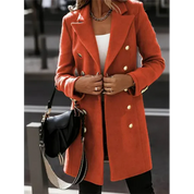 Cappotto arancione elegante da donna con bottoni dorati, indossato su top bianco. Accessoriato con borsa nera a tracolla. Moda autunnale chic.