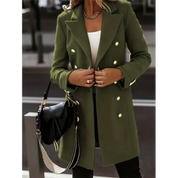 Cappotto verde militare da donna con bottoni dorati, indossato su top bianco. Accessori: borsa nera a tracolla. Look elegante e moderno.