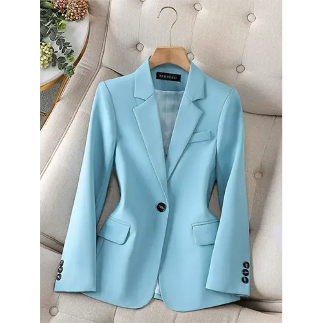 Giacca blazer donna azzurra elegante su sedia beige, con bottoni neri e tasche, ideale per abbigliamento formale e moda ufficio.