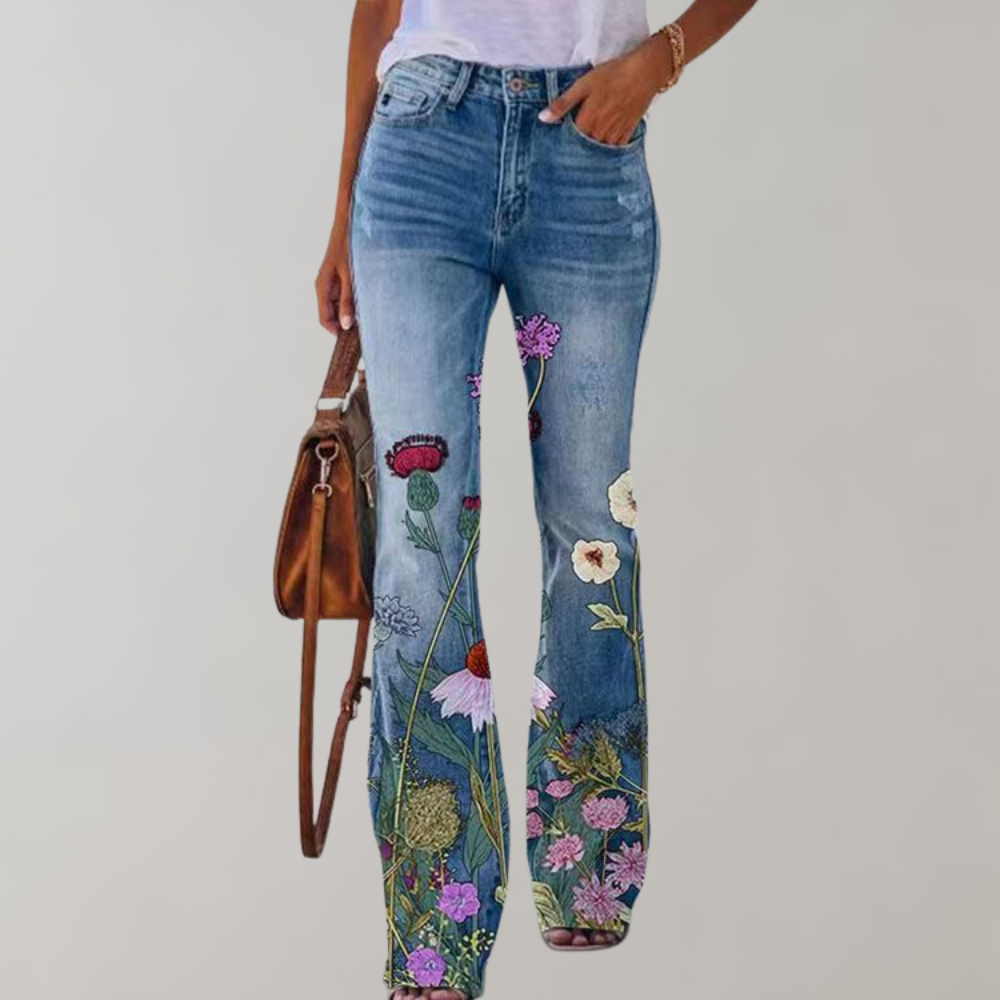 Jeans donna a zampa con ricami floreali colorati, abbinati a una borsa marrone e maglietta bianca. Stile casual, moda femminile trendy.