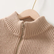 Maglione beige a collo alto con cerniera, lavorato a maglia, su appendiabiti in legno. Moda autunnale, abbigliamento caldo e confortevole.