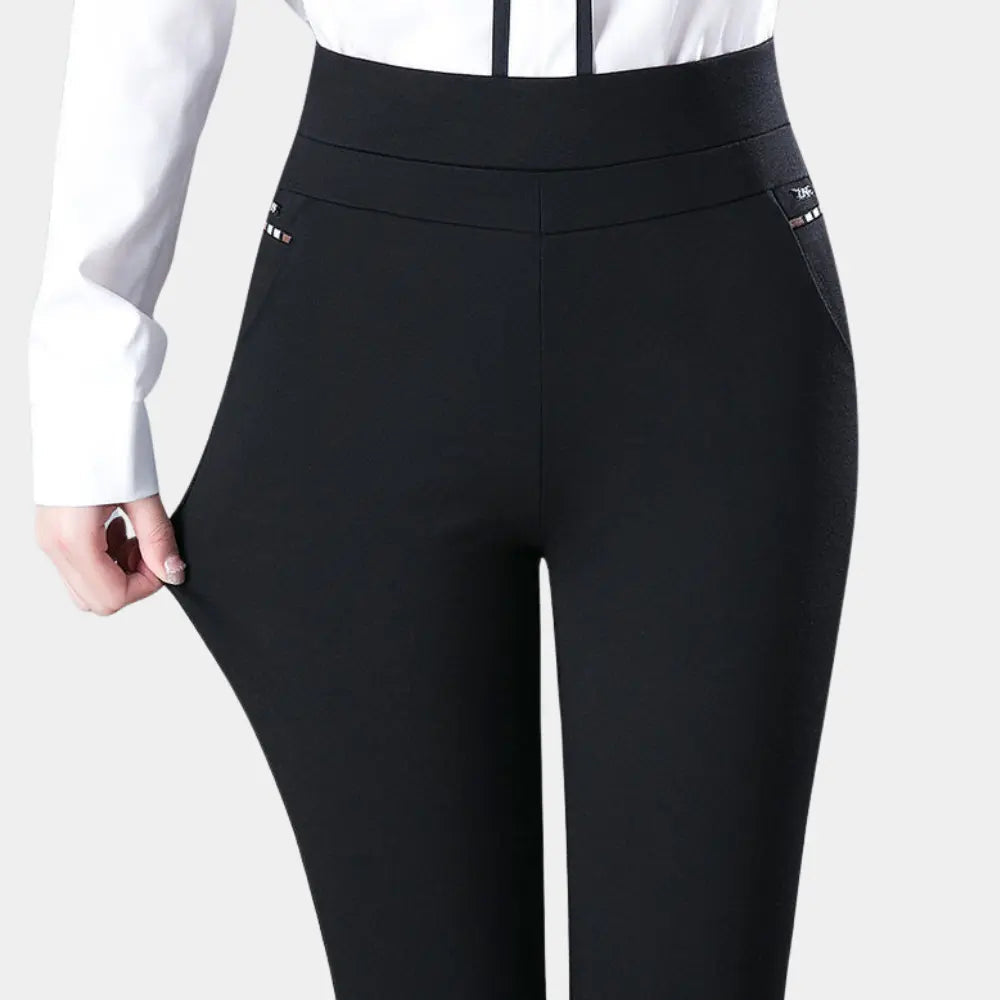 Pantaloni neri elasticizzati da donna, vita alta, con tasche laterali, indossati con camicia bianca. Moda femminile, abbigliamento elegante.