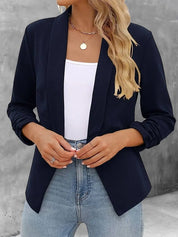 Donna con blazer nero elegante, top bianco e jeans. Moda casual chic, abbigliamento femminile, stile moderno. Sfondo grigio.