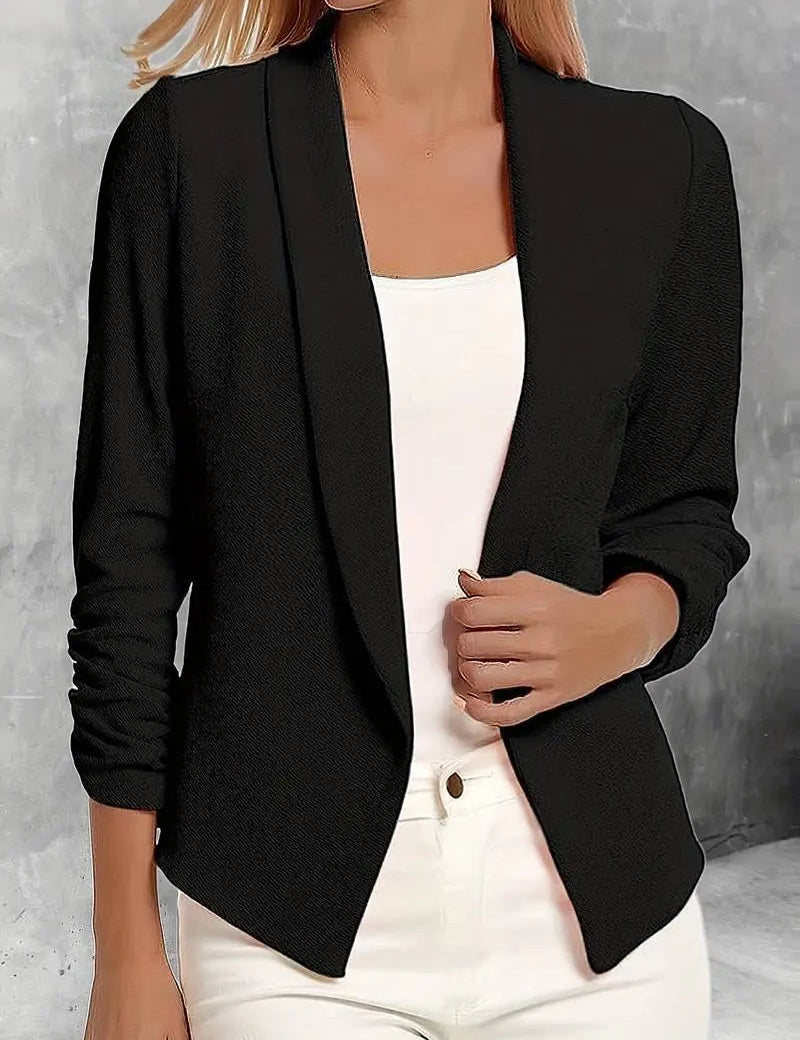Giacca blazer donna nera elegante, maniche lunghe, abbinata a top bianco e pantaloni chiari. Moda femminile, abbigliamento formale chic.