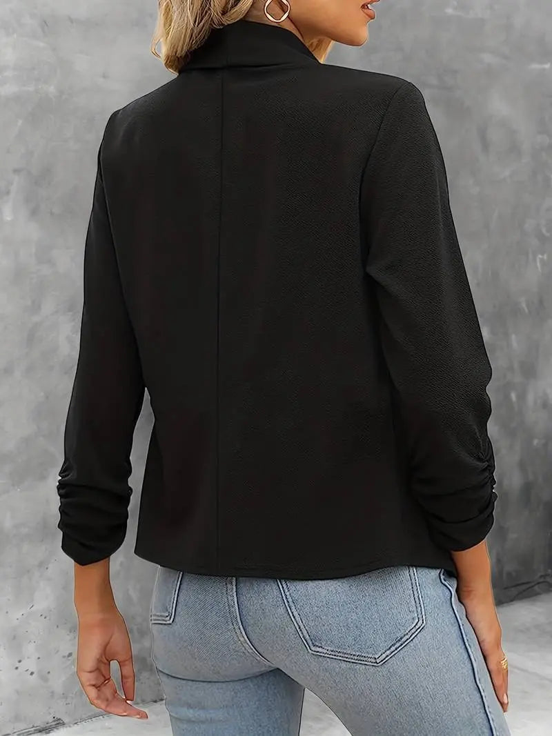 Giacca nera elegante da donna, maniche lunghe, abbinata a jeans chiari. Moda casual autunnale, stile versatile per ufficio o uscite serali.