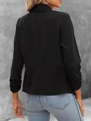 Giacca nera elegante da donna, maniche lunghe, abbinata a jeans chiari. Moda casual autunnale, stile versatile per ufficio o uscite serali.