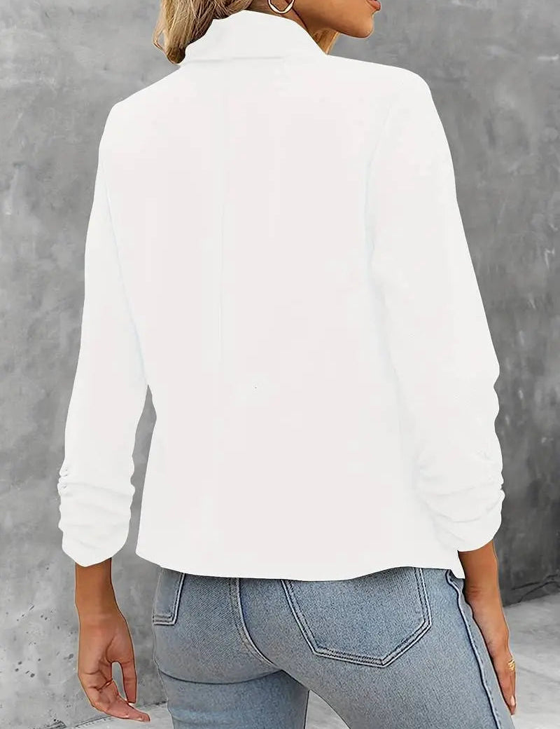 Giacca bianca da donna, maniche lunghe, collo alto, abbinata a jeans blu chiaro. Moda casual elegante, ideale per l'autunno.
