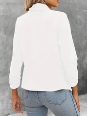 Giacca bianca da donna, maniche lunghe, collo alto, abbinata a jeans blu chiaro. Moda casual elegante, ideale per l'autunno.
