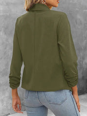 Giacca verde oliva da donna, maniche lunghe, collo alto, abbinata a jeans chiari. Stile casual elegante, tessuto morbido, moda autunnale.
