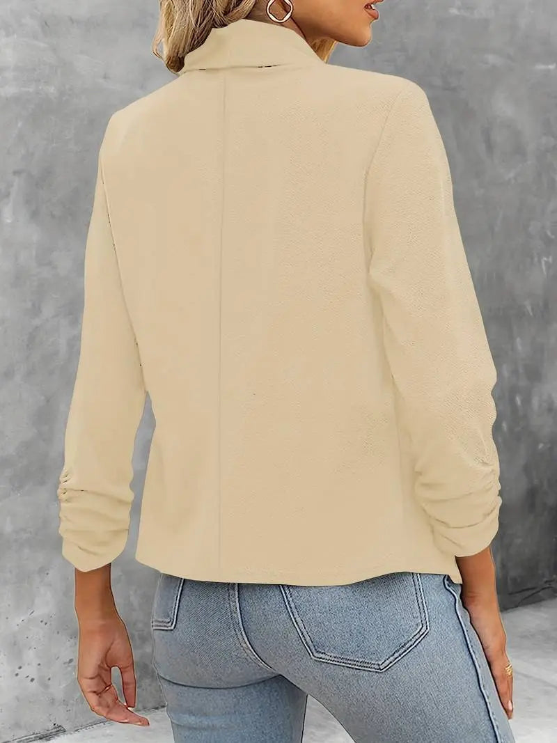 Giacca beige da donna, maniche lunghe, design elegante, abbinata a jeans blu. Moda casual autunnale, tessuto morbido, stile versatile.