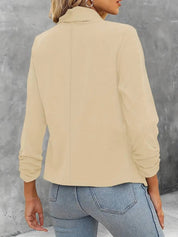 Giacca beige da donna, maniche lunghe, design elegante, abbinata a jeans blu. Moda casual autunnale, tessuto morbido, stile versatile.
