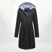 Cappotto impermeabile nero da donna con cappuccio, chiusura a zip, tasche frontali e fodera interna a righe. Elegante e funzionale per ogni stagione.