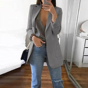 Giacca blazer grigia da donna, elegante e moderna, abbinata a jeans casual. Perfetta per look business casual o moda urbana.