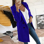 Donna con cappotto blu elegante, jeans e top bianco in una stanza moderna. Moda autunnale, abbigliamento casual chic.