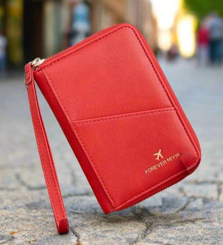 Portafoglio rosso in pelle con cerniera, design elegante, marchio "FOREVER MYWAY", sfondo urbano sfocato. Accessorio moda donna.