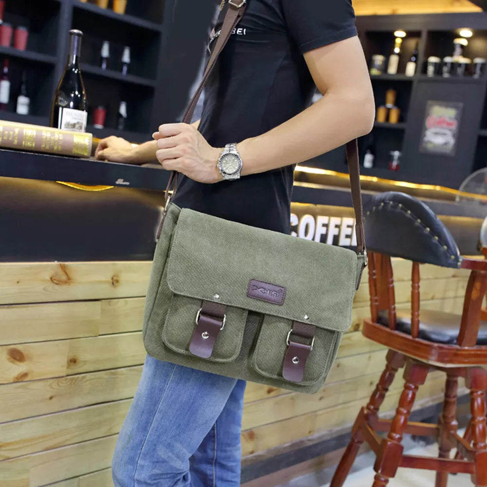 Borsa a tracolla verde in tela con fibbie marroni, indossata da uomo in un bar. Accessorio moda casual, ideale per lavoro o tempo libero.