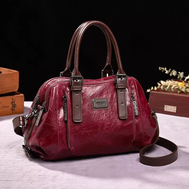 Borsa a mano in pelle rossa con manici marroni, design elegante, chiusura a zip, dettagli metallici, ideale per moda donna e accessori di lusso.