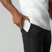Uomo inserisce smartphone bianco in tasca pantaloni neri. Tecnologia mobile, design elegante, accessorio quotidiano, praticità portatile.