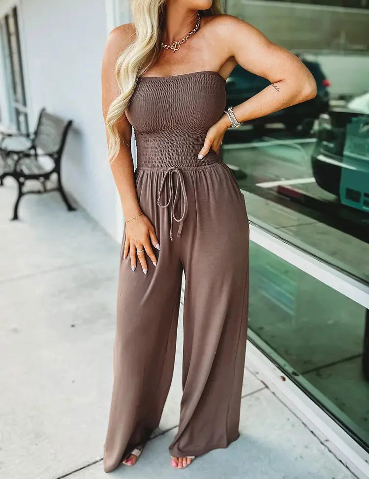 Donna con tuta marrone senza spalline, pantaloni larghi, posa all'aperto. Moda estiva, abbigliamento casual elegante, tendenza femminile 2023.