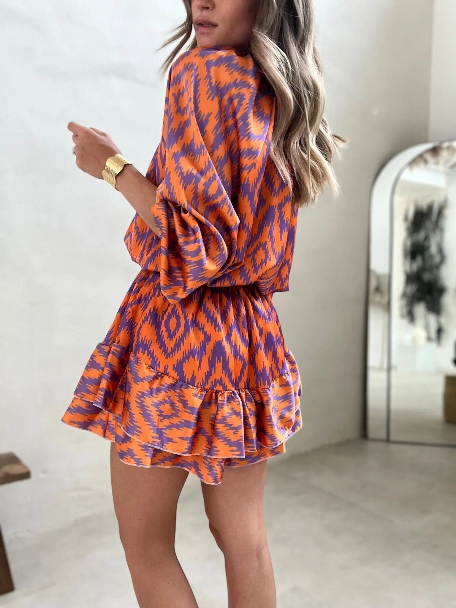 Abito corto donna arancione e viola con motivo geometrico, maniche lunghe, indossato da modella. Moda femminile, abbigliamento estivo elegante.