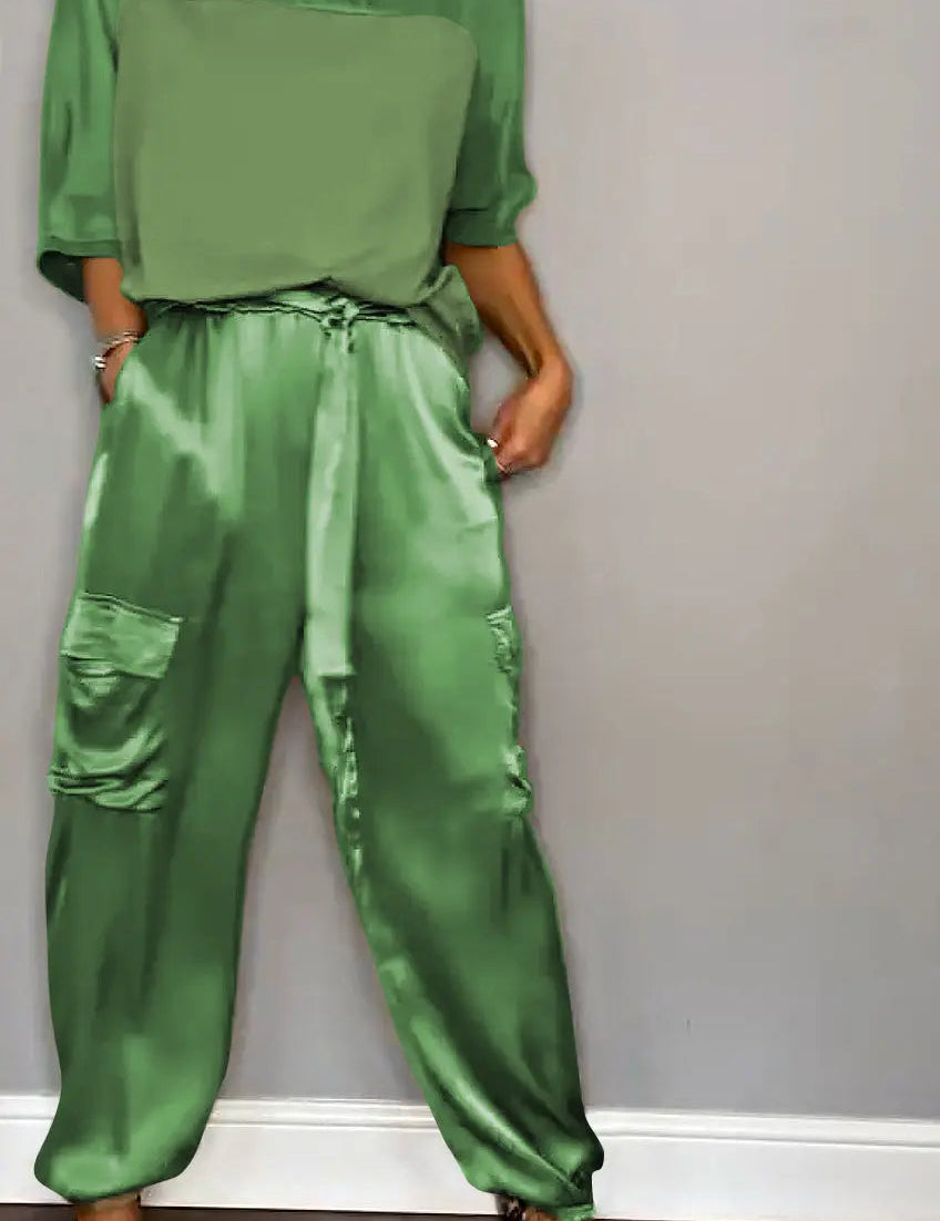 Donna con tuta verde satinata, tasche cargo, maniche corte, abbinata a tacchi leopardati. Moda elegante, abbigliamento femminile trendy.