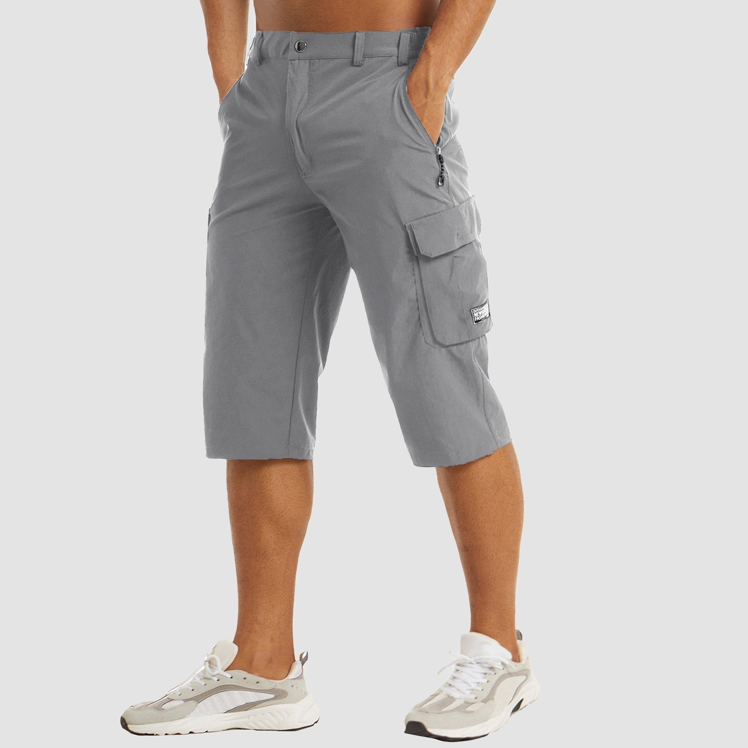 Bermuda cargo uomo grigio, tasche multiple, lunghezza al ginocchio, tessuto leggero, stile casual, perfetto per estate, abbinato a sneakers bianche.