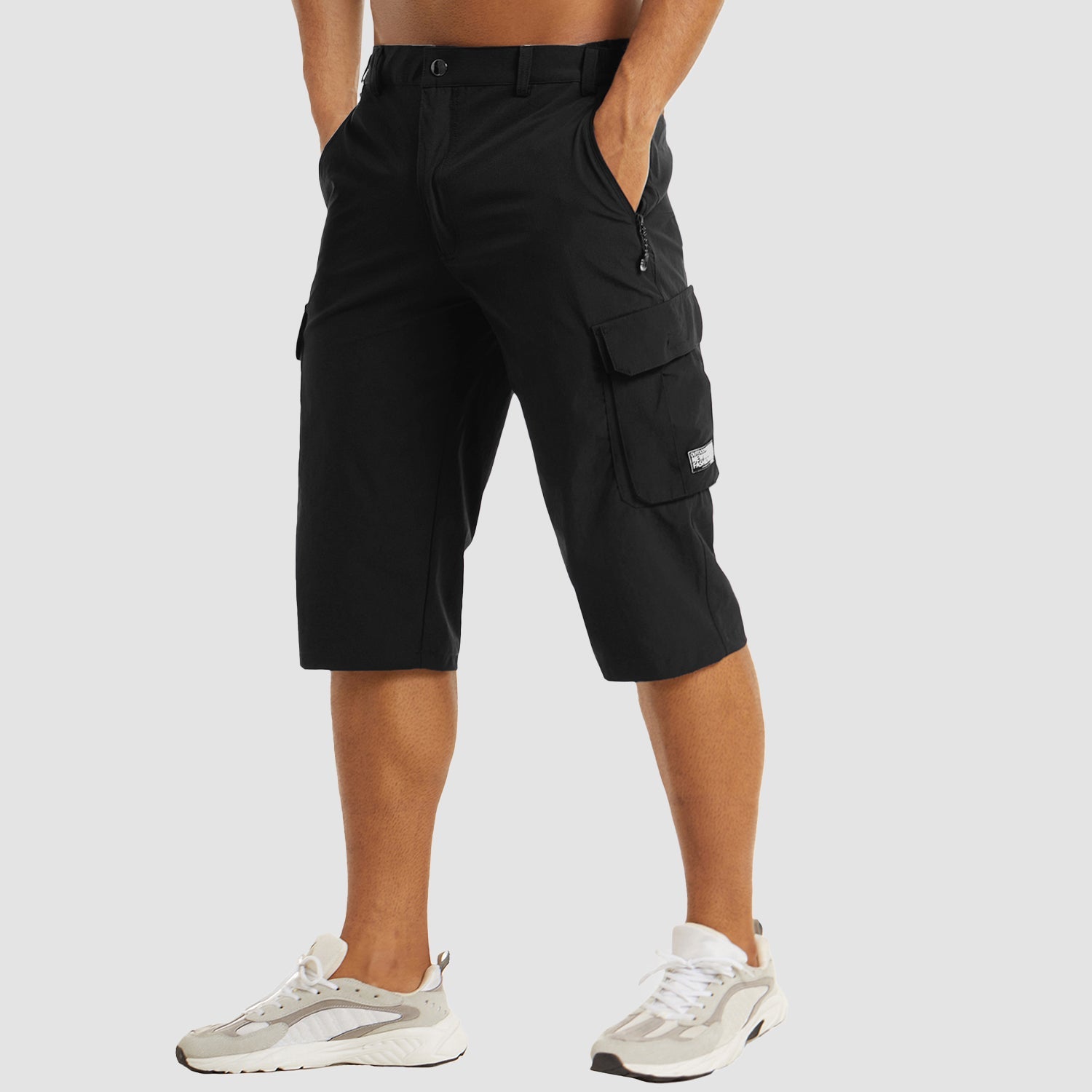 Pantaloncini cargo neri da uomo, tasche multiple, lunghezza al ginocchio, stile casual, abbinati a scarpe sportive bianche.