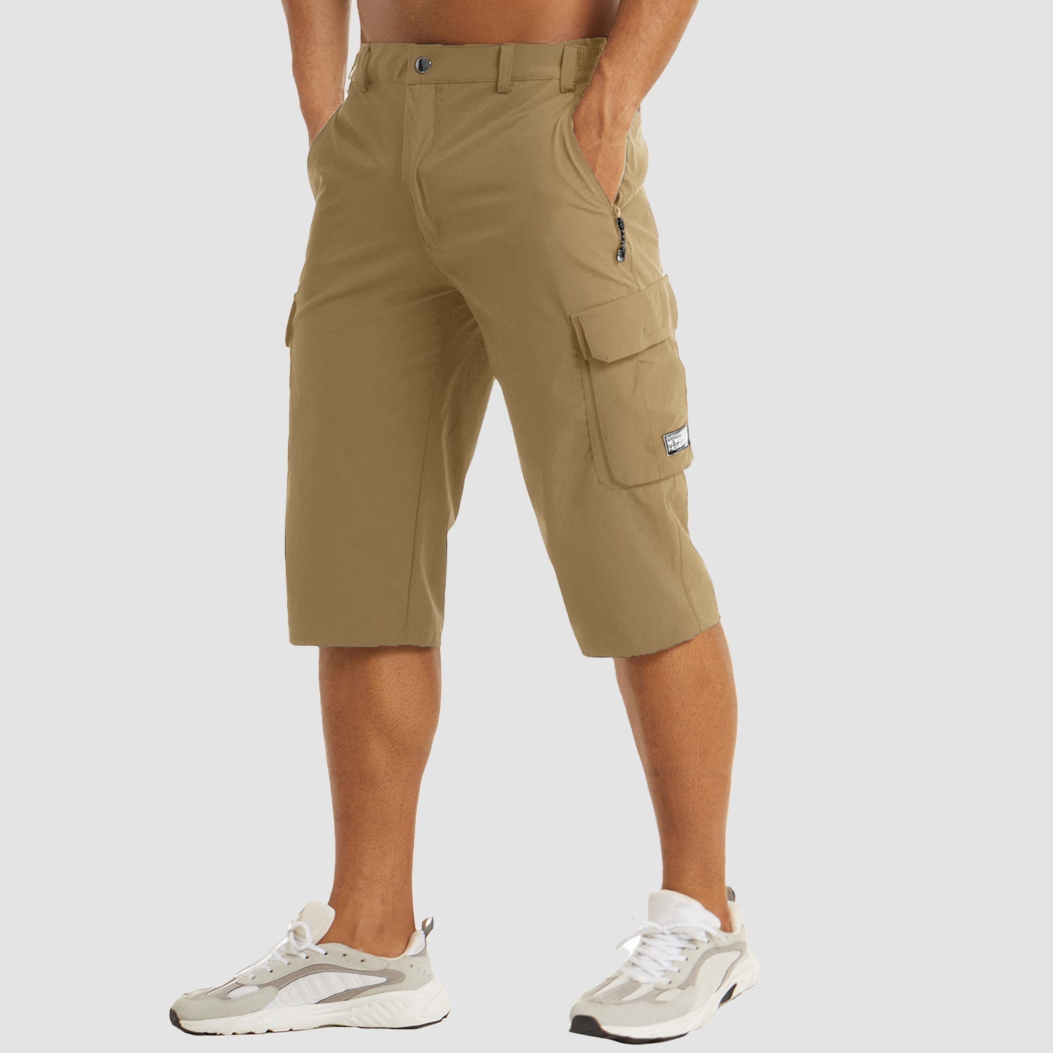 Pantaloncini cargo beige da uomo, lunghezza al ginocchio, con tasche laterali e chiusura zip, indossati con scarpe sportive bianche.