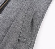 Giacca in tessuto grigio a spina di pesce con cerniera nera e tasca laterale. Elegante e moderna, ideale per abbigliamento formale e casual.