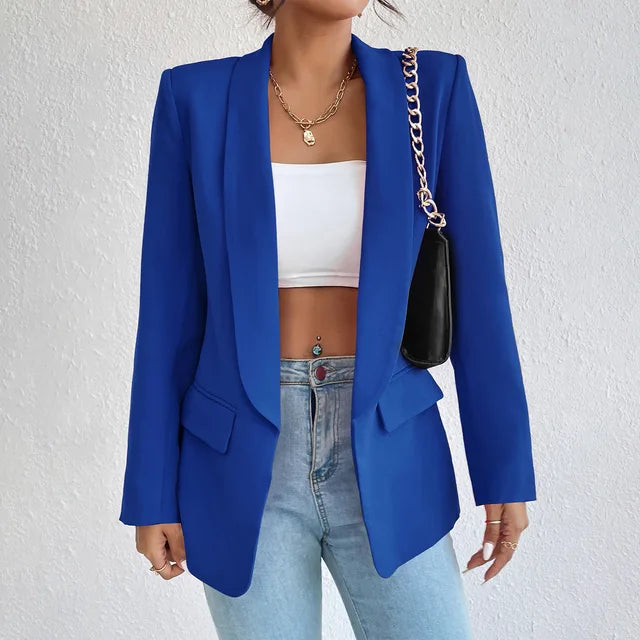 Giacca blazer blu da donna, elegante e moderna, abbinata a top bianco e jeans chiari. Accessorio borsa nera con catena dorata. Moda femminile casual.