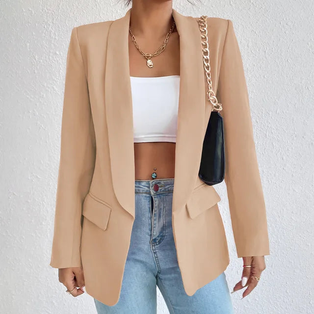 Giacca blazer beige da donna, elegante e moderna, abbinata a top bianco e jeans. Accessori: collana dorata e borsa a catena. Moda casual chic.