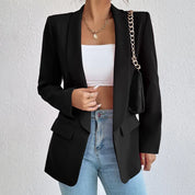 Giacca blazer nero elegante donna, abbinata a top bianco e jeans. Accessori: collana oro, borsa a tracolla con catena. Moda casual chic.