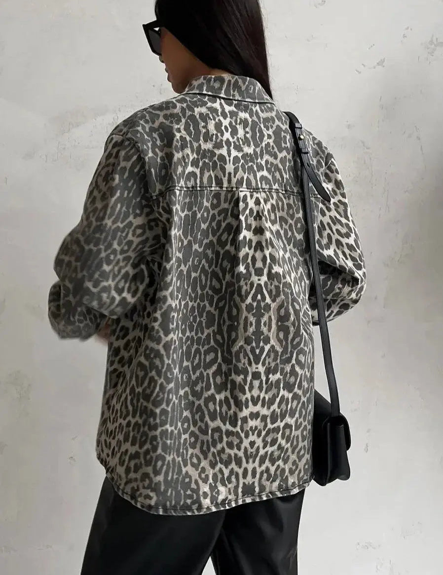 Giacca donna stampa leopardata, moda autunno, stile casual, sfondo grigio, borsa a tracolla nera, occhiali da sole, look urbano trendy.