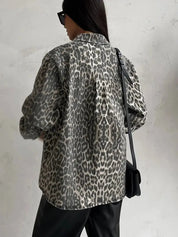 Giacca donna stampa leopardata, moda autunno, stile casual, sfondo grigio, borsa a tracolla nera, occhiali da sole, look urbano trendy.