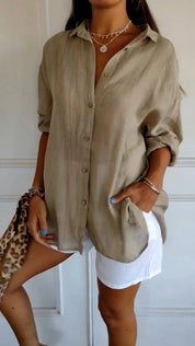 Camicia beige a maniche lunghe in lino, abbinata a pantaloncini bianchi. Look estivo casual, moda donna, stile elegante e rilassato.