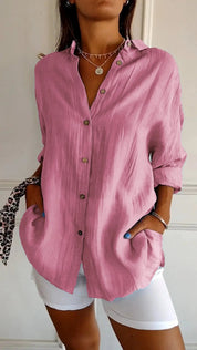 Camicia donna rosa a maniche lunghe, bottoni frontali, tessuto leggero, abbinata a pantaloni bianchi. Stile casual elegante, moda femminile.