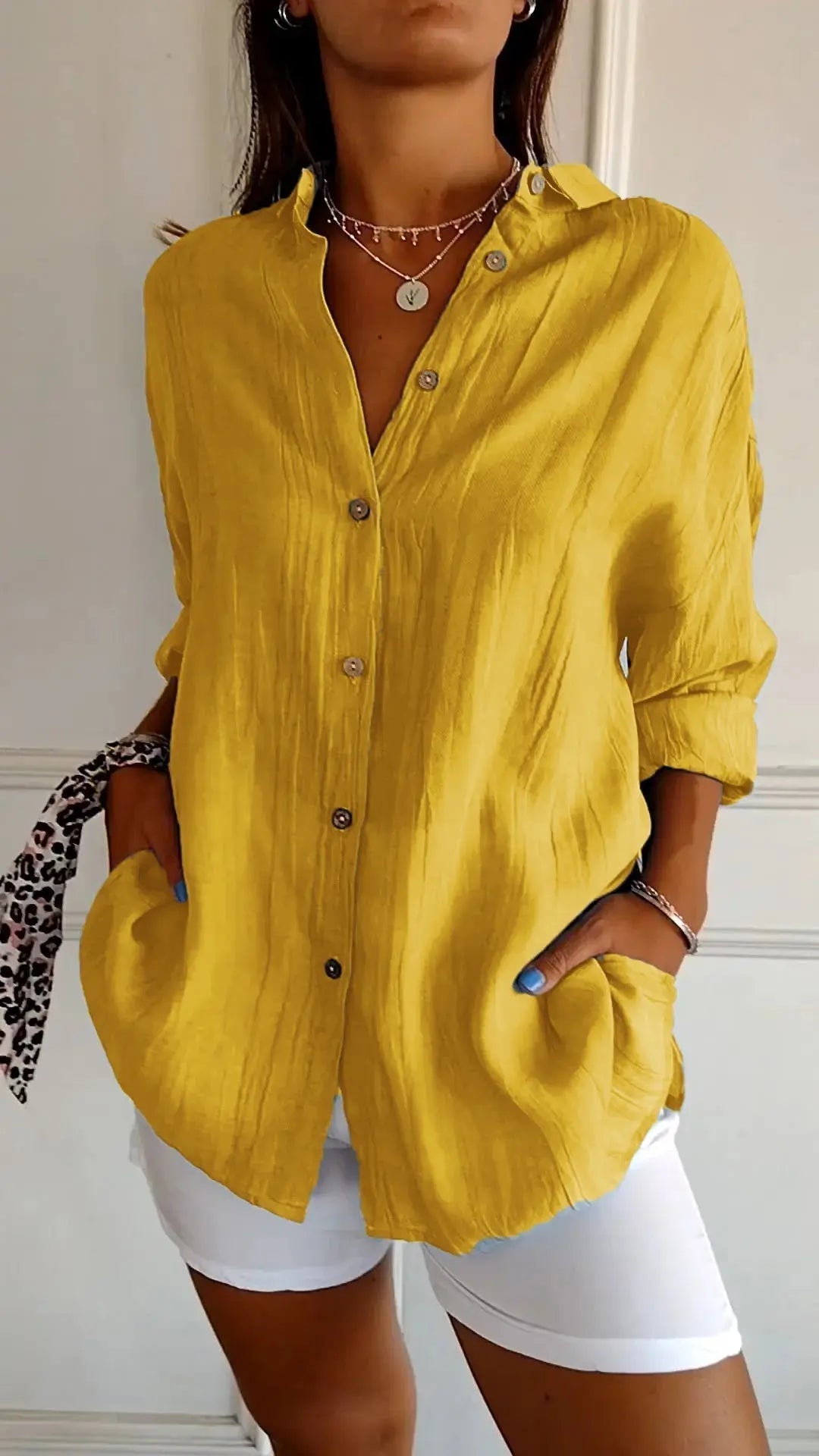 Camicia gialla da donna in lino, maniche lunghe, bottoni frontali, abbinata a pantaloni bianchi. Stile casual elegante, moda estiva.