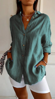 Camicia verde donna in lino, maniche lunghe, bottoni frontali, tasche laterali, abbinata a pantaloni bianchi. Stile casual elegante.