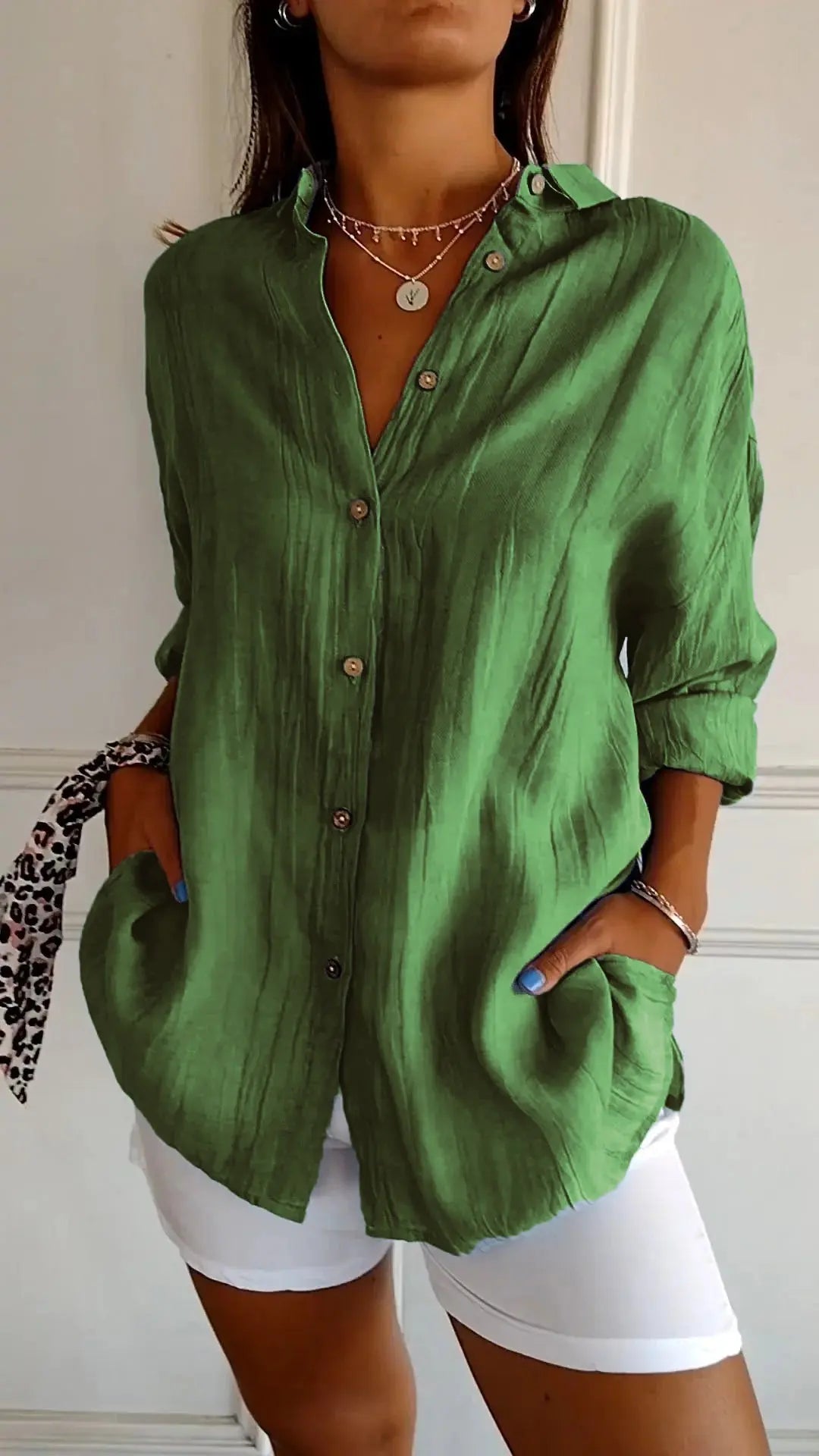 Camicia verde in lino con bottoni, maniche lunghe, tasche frontali, abbinata a pantaloni bianchi. Stile casual elegante, moda donna.