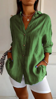 Camicia verde in lino con bottoni, maniche lunghe, tasche frontali, abbinata a pantaloni bianchi. Stile casual elegante, moda donna.
