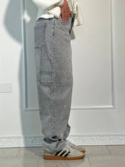 Jeans grigi con strass, tasche laterali, indossati con sneakers bianche e nere. Moda casual, abbigliamento uomo, stile urbano.